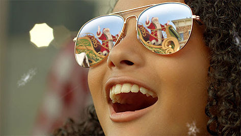 Santa and his sleigh reflected in young girls sunglasses