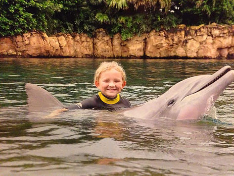 child happily swimming with dolphin
