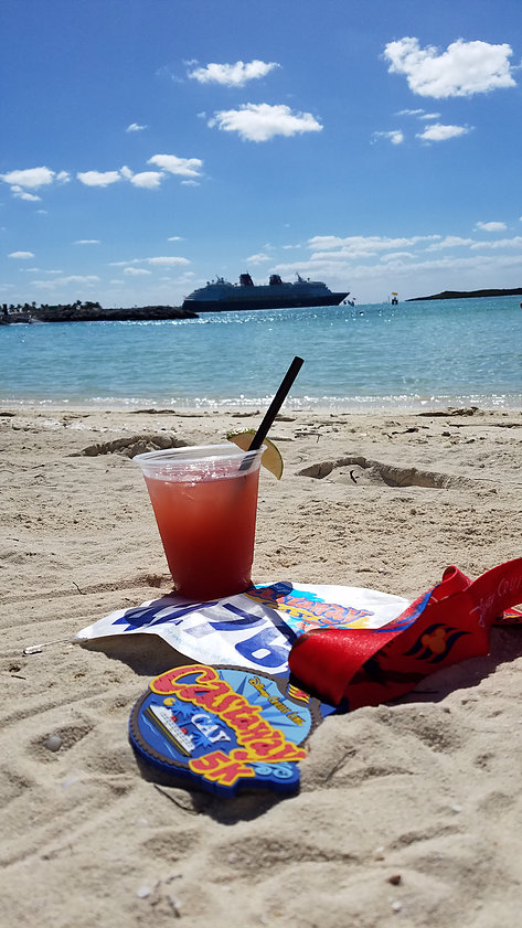cocktail and race name tag on the beach with view of DCL ship