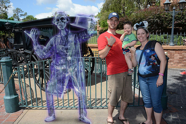 family posing with the projected image of a ghost at Disney