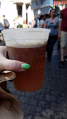 hand holding a glass of cold butterbeer